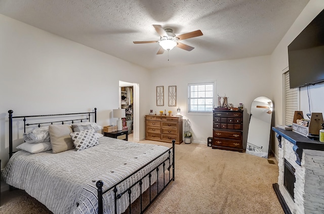 carpeted bedroom featuring ceiling fan, a textured ceiling, a closet, and a walk in closet