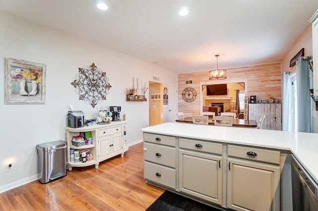 kitchen with light wood-type flooring, wooden walls, an inviting chandelier, and pendant lighting