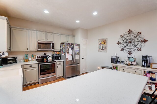 kitchen with gray cabinets, light wood-type flooring, and stainless steel appliances