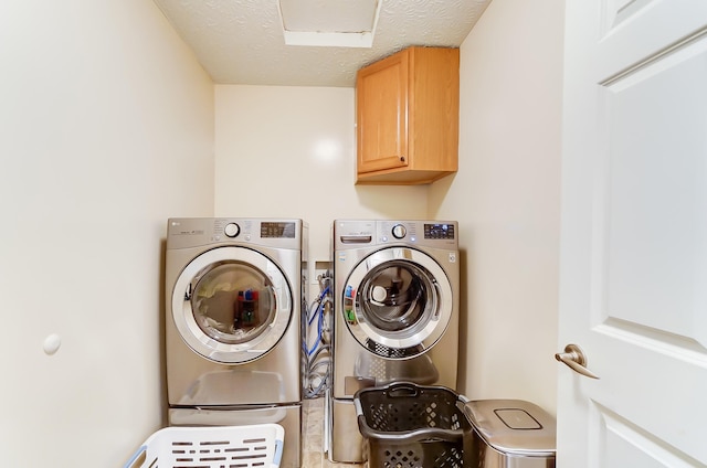 laundry area featuring washer and dryer, cabinets, and a textured ceiling