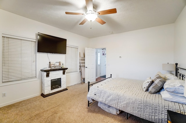 carpeted bedroom with a fireplace, a textured ceiling, and ceiling fan