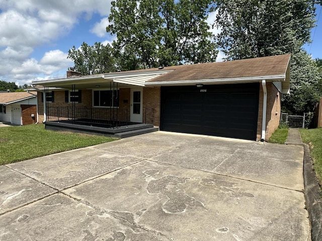 2336 Derr Rd, Springfield, OH 45503 - ranch-style home featuring brick siding, a garage, a porch, and concrete driveway