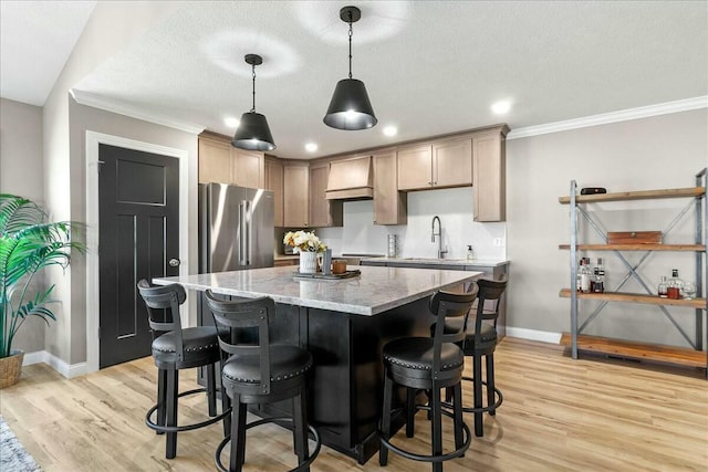 kitchen with stainless steel fridge, light stone counters, light wood-style flooring, and a center island