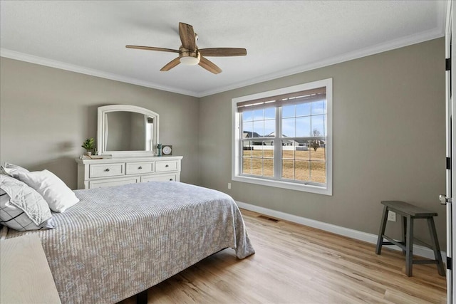 bedroom featuring baseboards, visible vents, a ceiling fan, ornamental molding, and light wood-type flooring