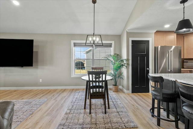 dining area with baseboards, a notable chandelier, and light wood finished floors