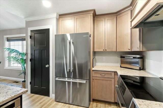 kitchen featuring custom range hood, freestanding refrigerator, light stone countertops, light wood-type flooring, and backsplash