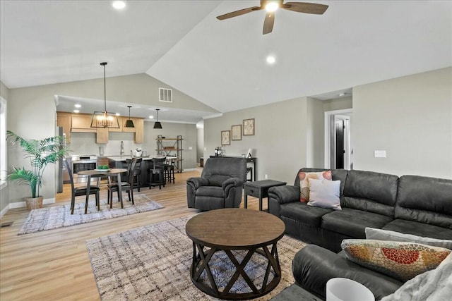 living room with high vaulted ceiling, light wood-style flooring, visible vents, baseboards, and a ceiling fan