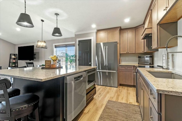 kitchen with a breakfast bar, light wood finished floors, stainless steel appliances, a kitchen island, and light stone countertops