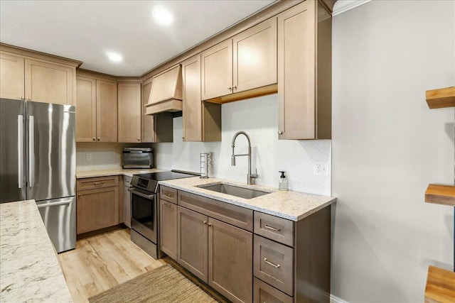 kitchen featuring light wood-style flooring, appliances with stainless steel finishes, light stone countertops, custom exhaust hood, and a sink