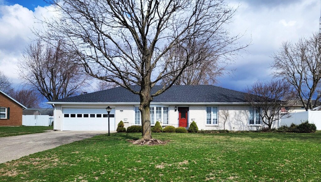 ranch-style home featuring brick siding, a garage, concrete driveway, and fence