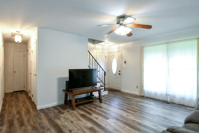 living area featuring baseboards, ceiling fan, wood finished floors, and stairway
