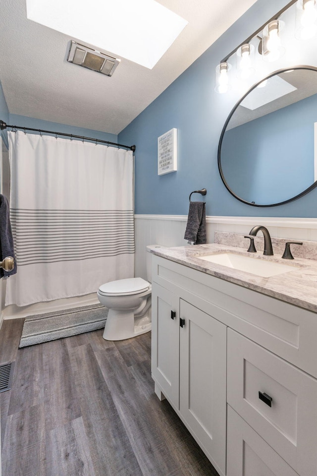 11851 Sanders Rd, Richwood, OH 43344 - bathroom featuring wainscoting, vanity, toilet, wood finished floors, and a skylight