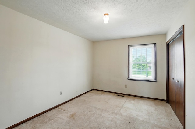 1985 Fox Run, Troy, OH 45373 - unfurnished bedroom featuring light carpet, a closet, and a textured ceiling