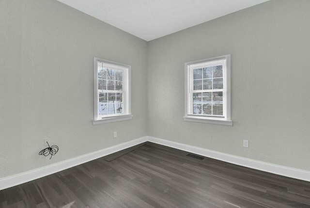 spare room with plenty of natural light and dark hardwood / wood-style floors