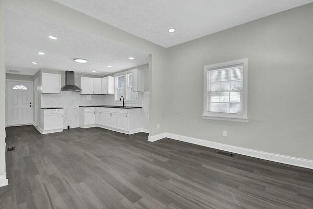 kitchen with wall chimney exhaust hood, sink, dark hardwood / wood-style flooring, white cabinets, and backsplash