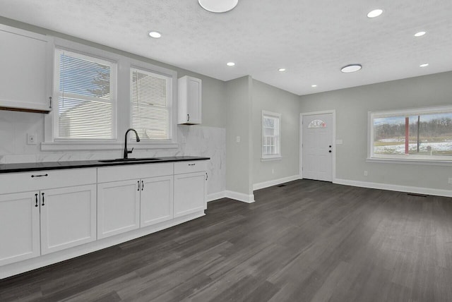 kitchen featuring white cabinetry, sink, backsplash, dark hardwood / wood-style flooring, and a textured ceiling