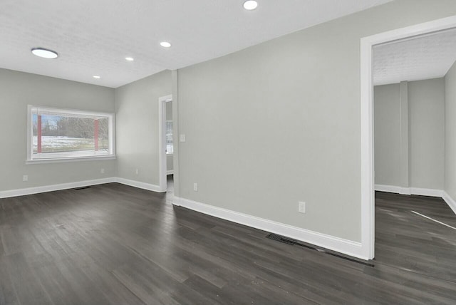 unfurnished room featuring dark hardwood / wood-style flooring and a textured ceiling