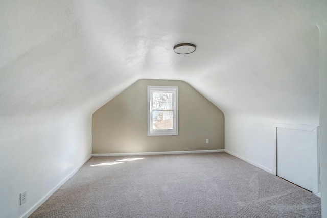 additional living space featuring carpet flooring, baseboards, and vaulted ceiling