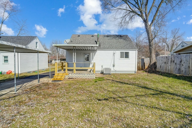 rear view of property featuring central air condition unit, a deck, fence, a yard, and roof with shingles