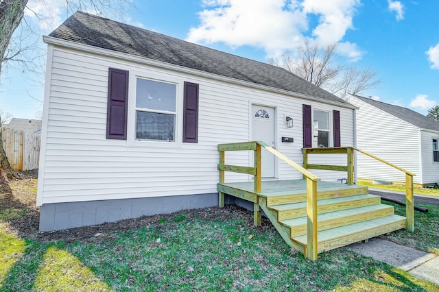 view of front of home featuring roof with shingles and fence