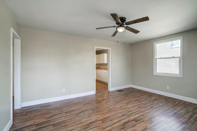 unfurnished room featuring a ceiling fan, visible vents, baseboards, and dark wood-style flooring