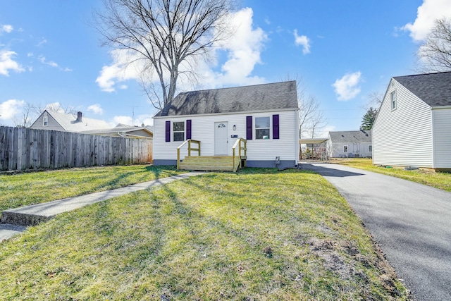 view of front of home featuring aphalt driveway, a front lawn, and fence