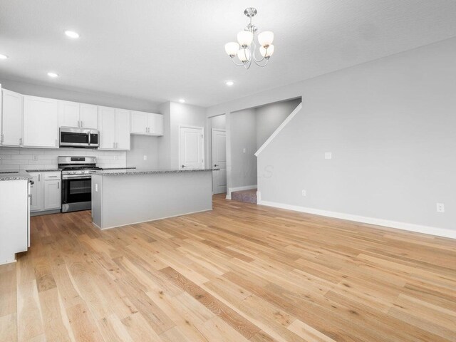 kitchen featuring a kitchen island, white cabinets, appliances with stainless steel finishes, decorative backsplash, and pendant lighting