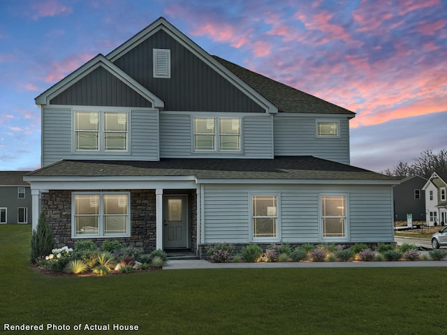 view of front of house featuring board and batten siding, a front yard, stone siding, and roof with shingles