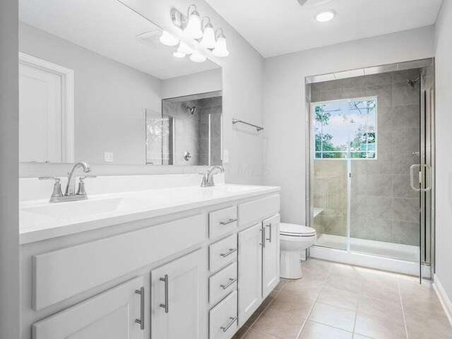 full bath featuring a stall shower, tile patterned flooring, a sink, and double vanity