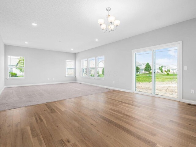 unfurnished living room with a chandelier, recessed lighting, light wood-style flooring, and baseboards