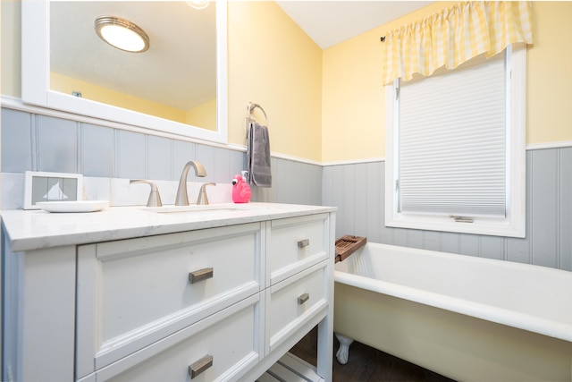 bathroom featuring vanity, a freestanding tub, and wainscoting