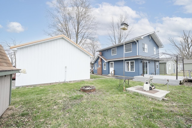 rear view of house with a fire pit and a yard