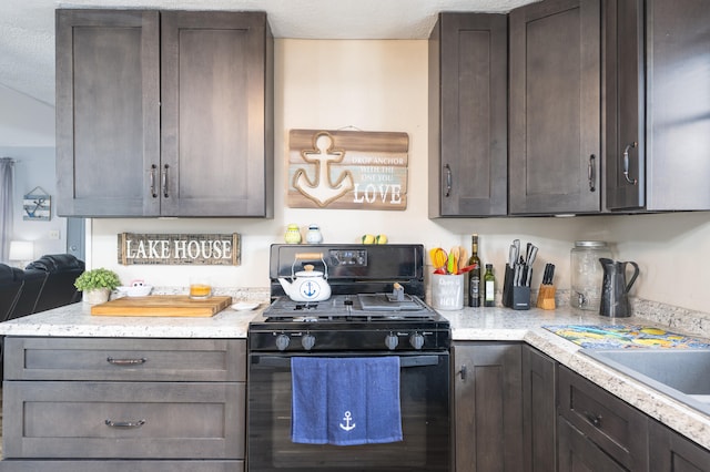 kitchen with dark brown cabinets, black range with gas cooktop, and light stone counters