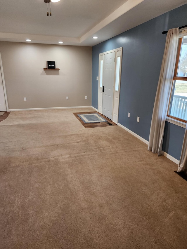 interior space featuring recessed lighting, a tray ceiling, and baseboards