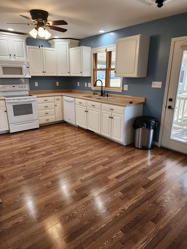 kitchen with white appliances, white cabinets, plenty of natural light, and a sink