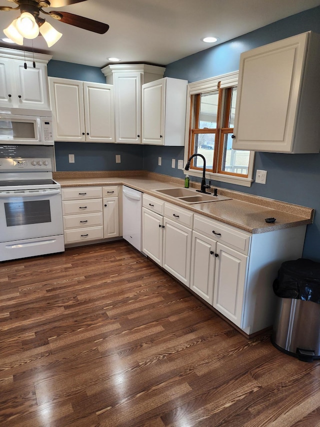 kitchen featuring dark wood-style flooring, white cabinets, white appliances, and a sink