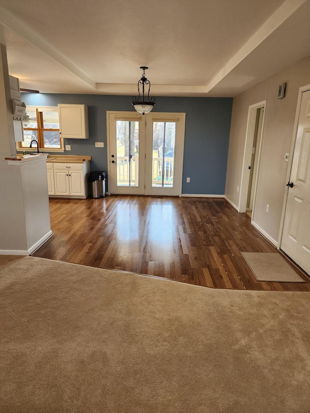 1114 Indiana Ave, Saint Marys, OH 45885 - unfurnished living room with a sink, a tray ceiling, baseboards, and dark wood-type flooring