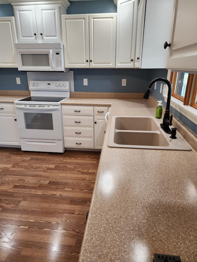 kitchen with a sink, white appliances, dark wood-type flooring, and white cabinetry