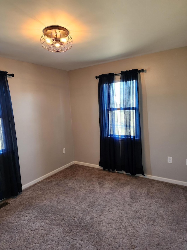 unfurnished room with carpet flooring, visible vents, and baseboards