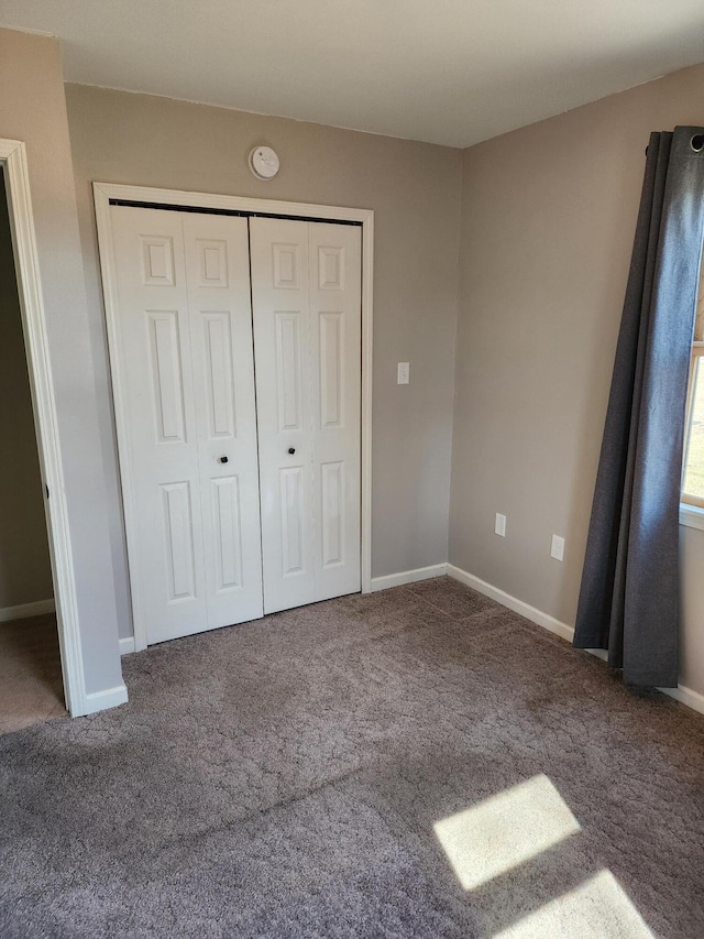 unfurnished bedroom with a closet, baseboards, and carpet