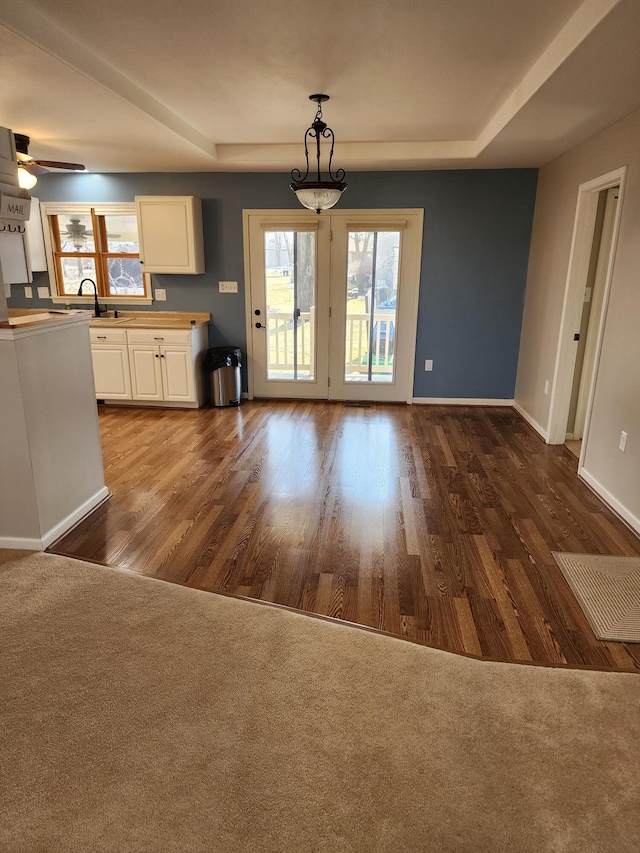 interior space featuring a sink, baseboards, a raised ceiling, and dark wood-style floors