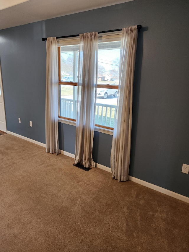 empty room featuring a healthy amount of sunlight, baseboards, and carpet floors