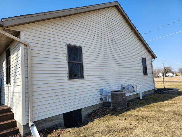 view of side of property featuring a yard and central AC