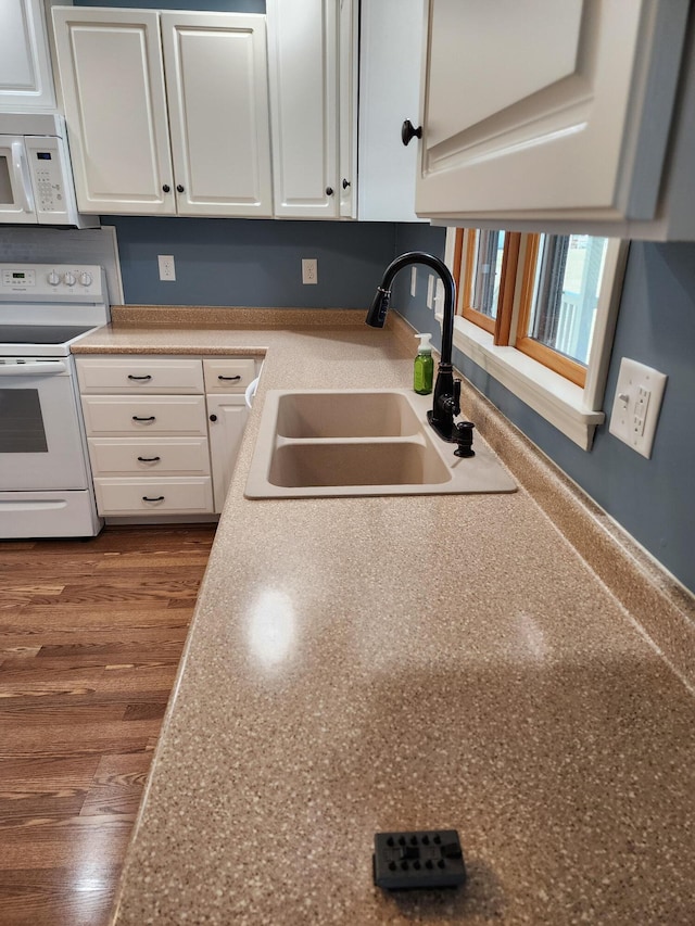 kitchen featuring dark wood finished floors, white cabinets, white appliances, and a sink