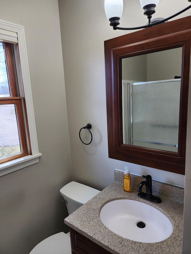 bathroom featuring vanity, toilet, and a shower with shower door