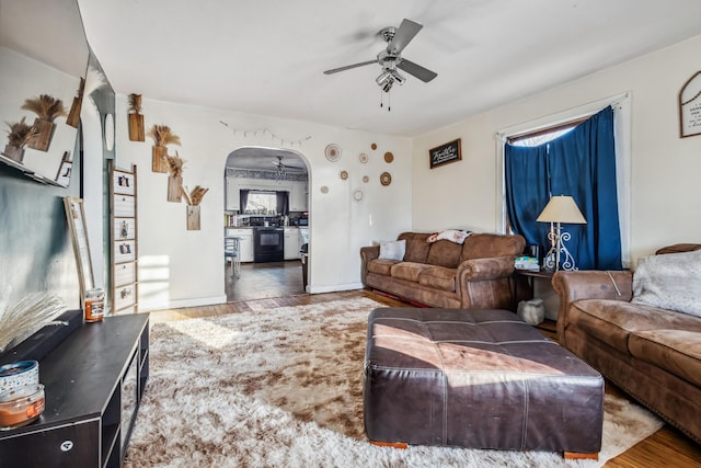 living room with arched walkways, a ceiling fan, and wood finished floors