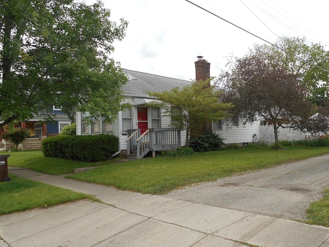 223 W Washington St, New Carlisle, OH 45344 - obstructed view of property featuring a chimney, a front lawn, and a shingled roof