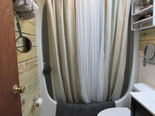 bathroom featuring wooden walls, shower / bathtub combination with curtain, and toilet