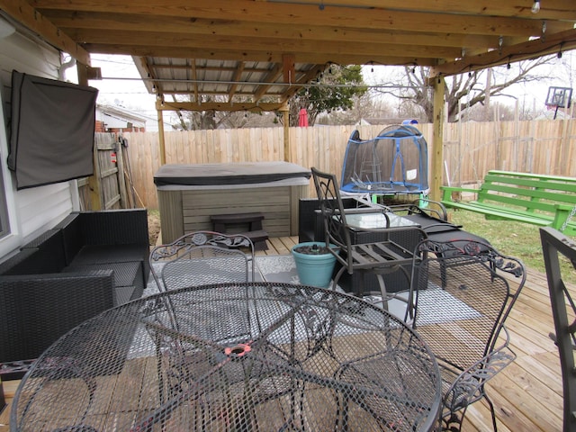 view of patio / terrace featuring a wooden deck, a hot tub, and a trampoline