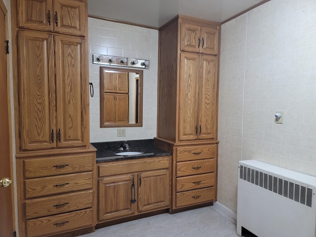 bathroom featuring vanity, radiator, and tile walls